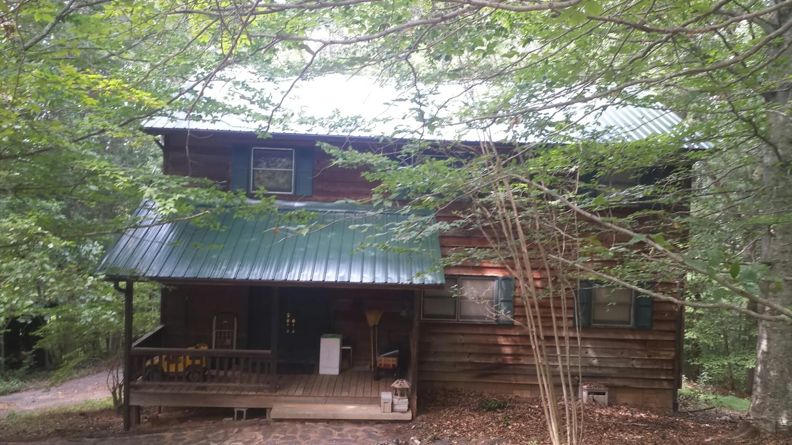 Green metal roof and covered porch on a log cabin in Inver Grove Heights
