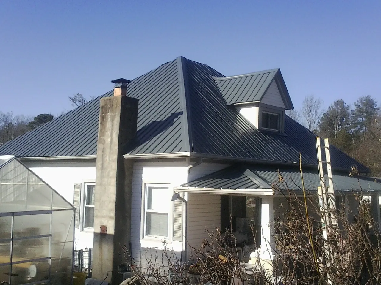 Dark blue standing seam metal roof on a white farmhouse with dormer — Slate & Tile Roof Repair by Roofing Brothers in Inver Grove Heights