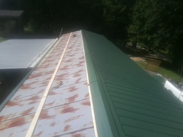 Old rusted panels beside newly installed green metal roofing — Wind Damage Roof Repair by Roofing Brothers in Inver Grove Heights