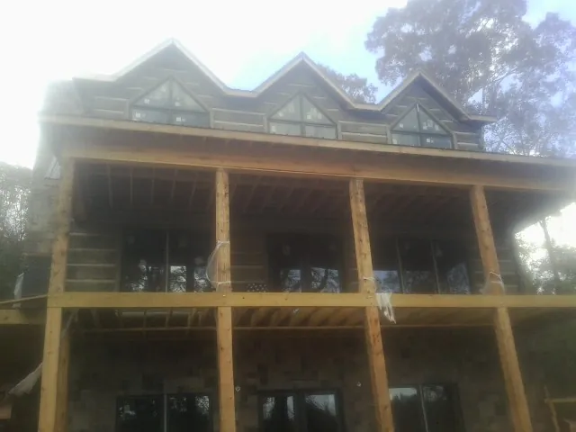 Dormers and porch framing on a large log home under construction — Roof Coating work by our crew in Inver Grove Heights