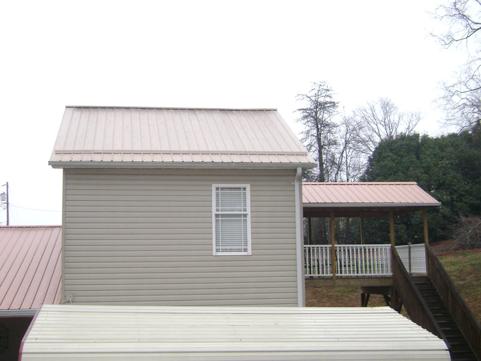 Tan metal roofs on a two story addition and attached porch, from a Roof Replacement job in Inver Grove Heights