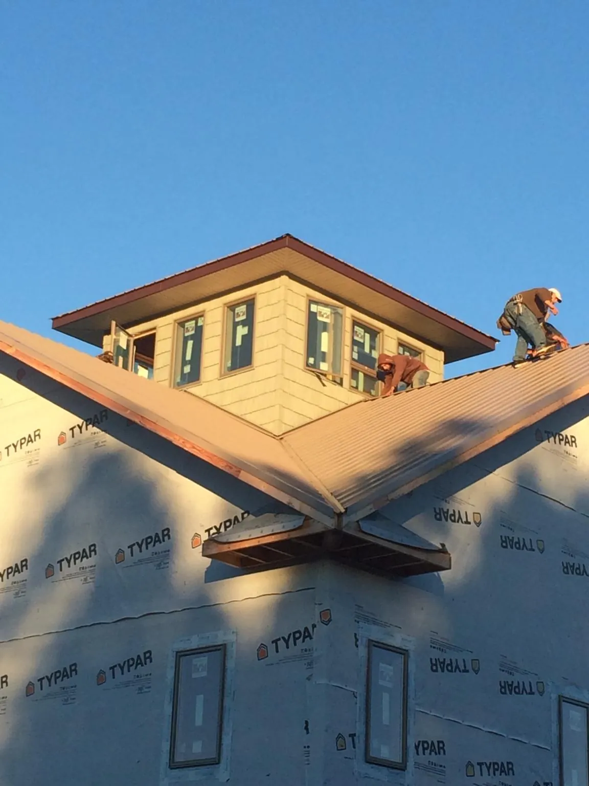 Roofers working around a rooftop cupola on a new metal roof at sunset — Roof Waterproofing in Inver Grove Heights by Roofing Brothers